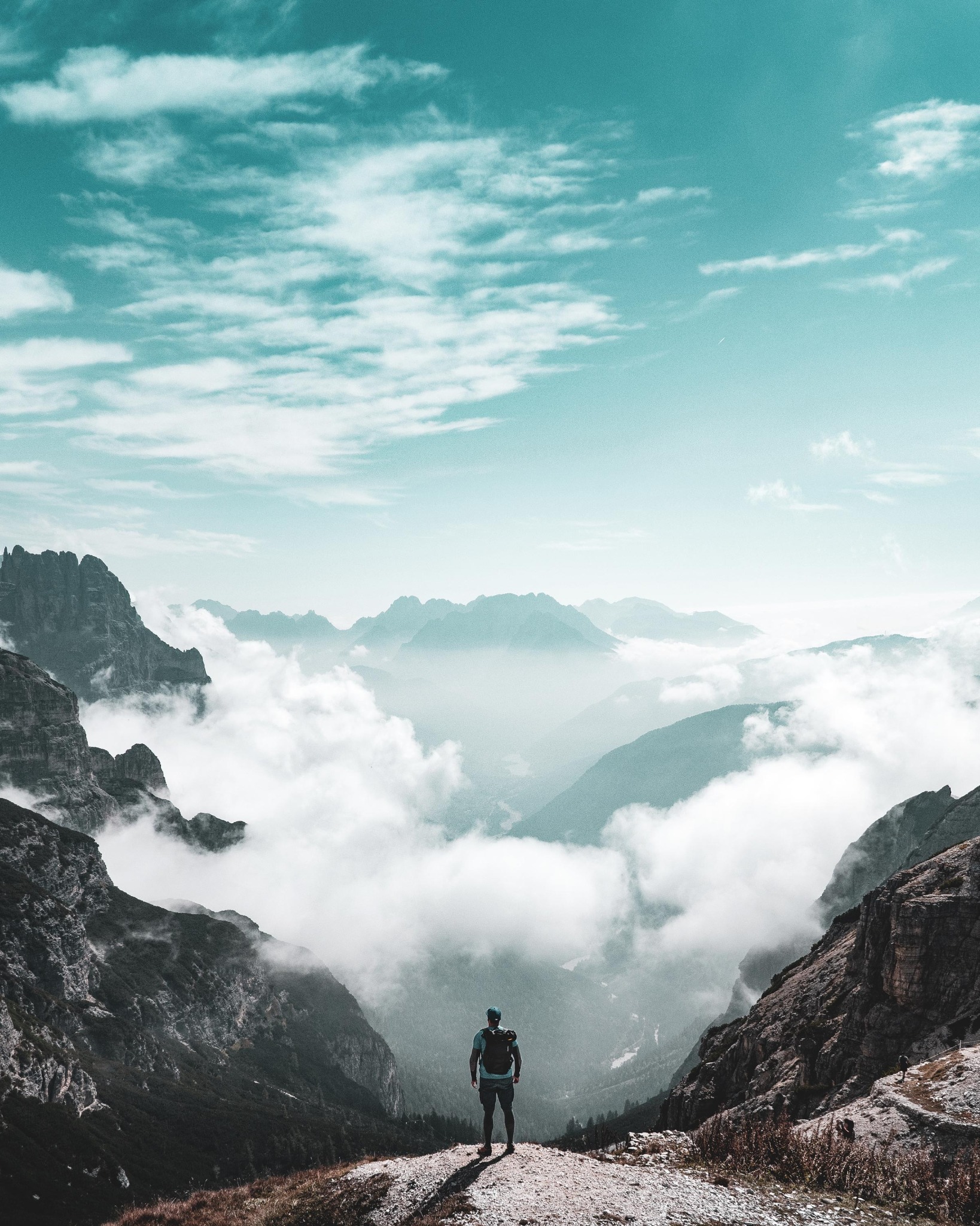 Hiker overlooking mountain peaks above the clouds