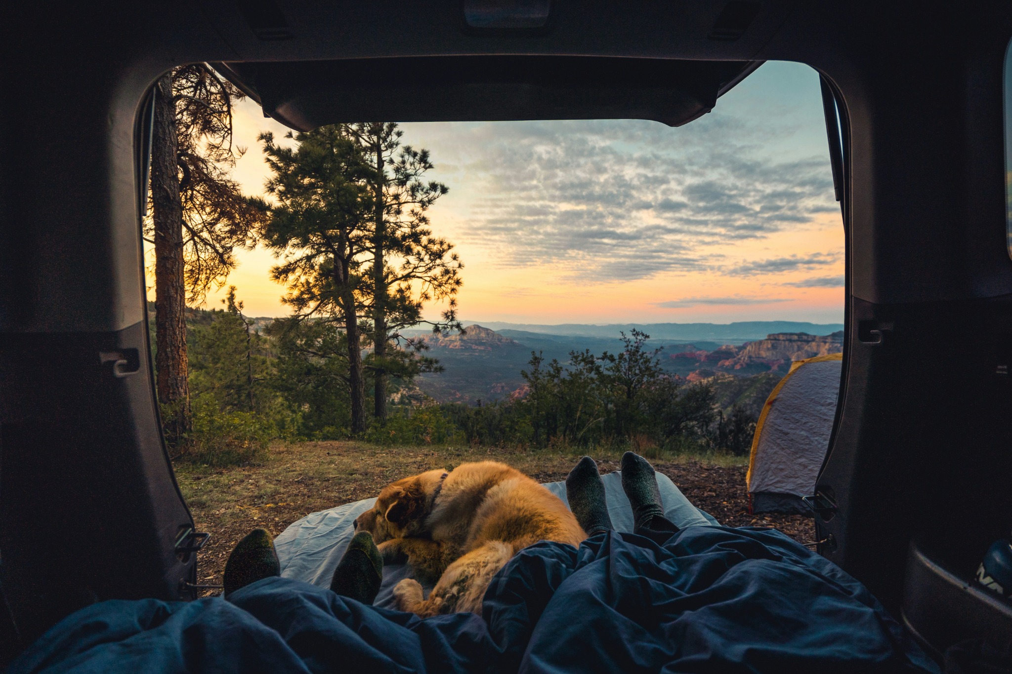 Camping view from the back of a vehicle overlooking a mountain landscape
