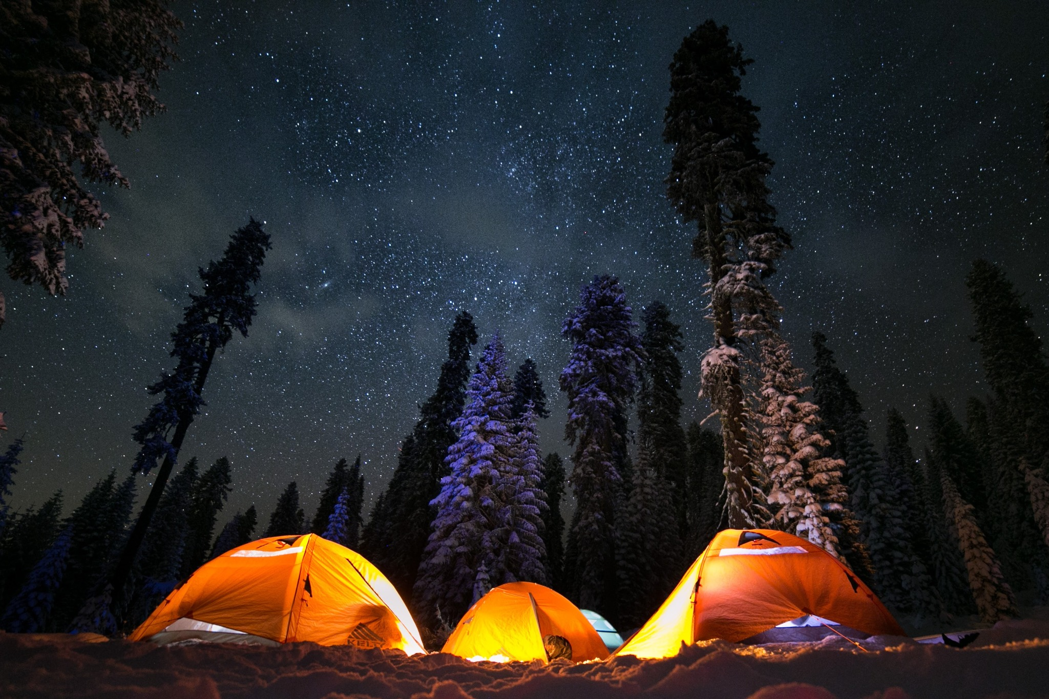 Illuminated tents beneath a star-filled winter sky