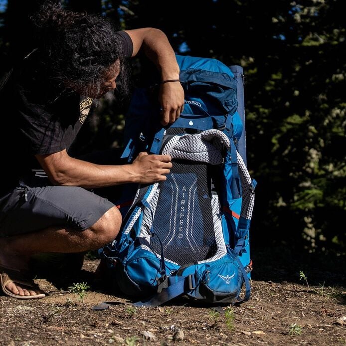 Hiker adjusting the suspended mesh harness of an Osprey Atmos AG LT backpack
