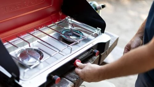 A cook adjusting the Camp Chef Everest 2X burner control