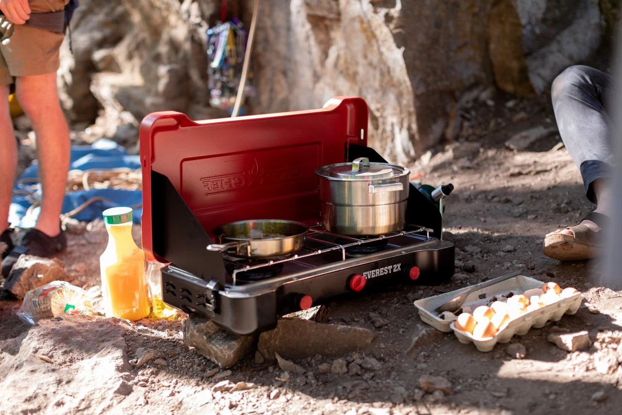 Camp Chef Everest 2X holding a frying pan and lidded pot at camp