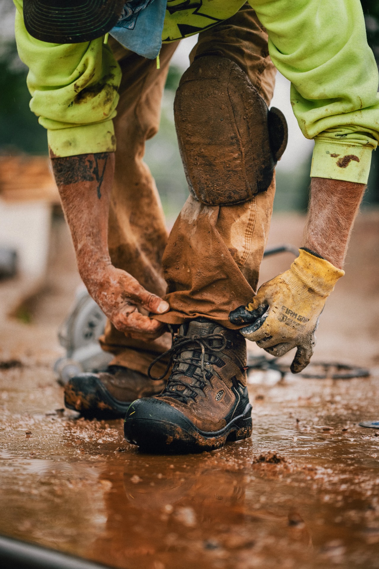 Worker fastening trousers over muddy KEEN Targhee IV Work boots
