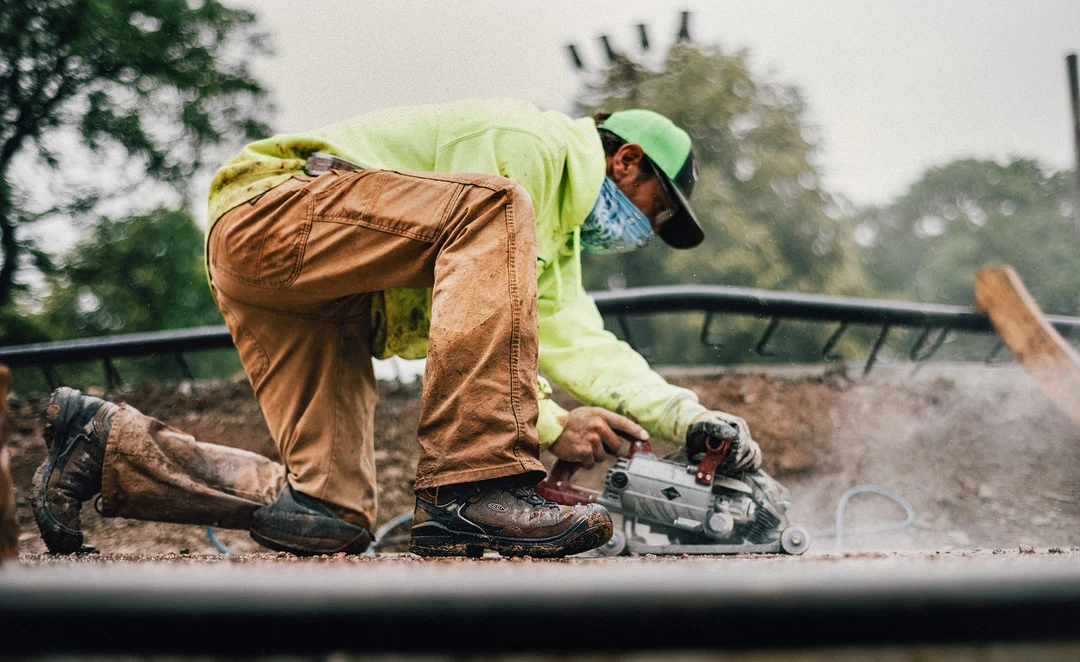 Worker kneeling in KEEN Targhee IV Work boots beside power tools