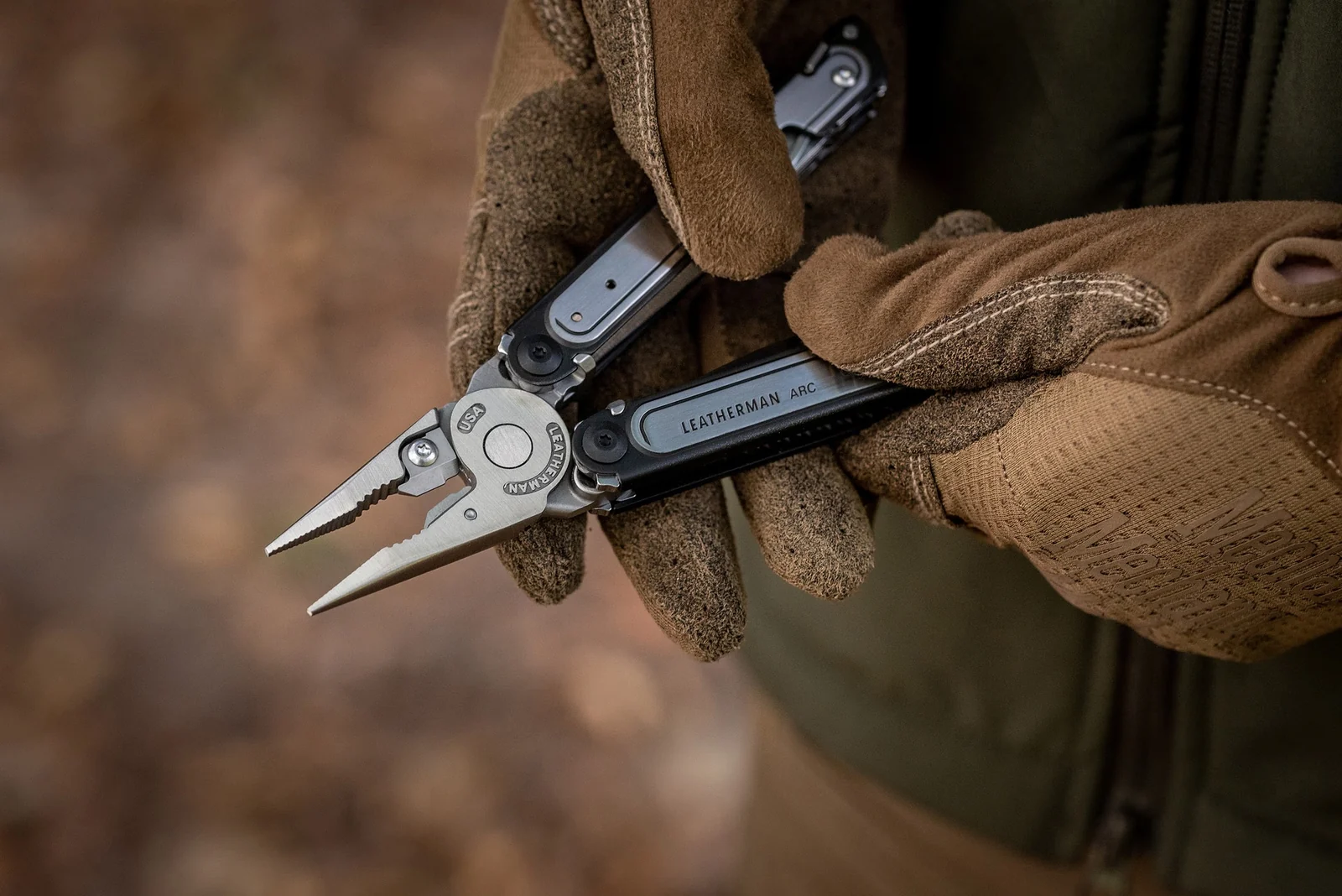 Leatherman ARC multitool pliers opened in gloved hands outdoors