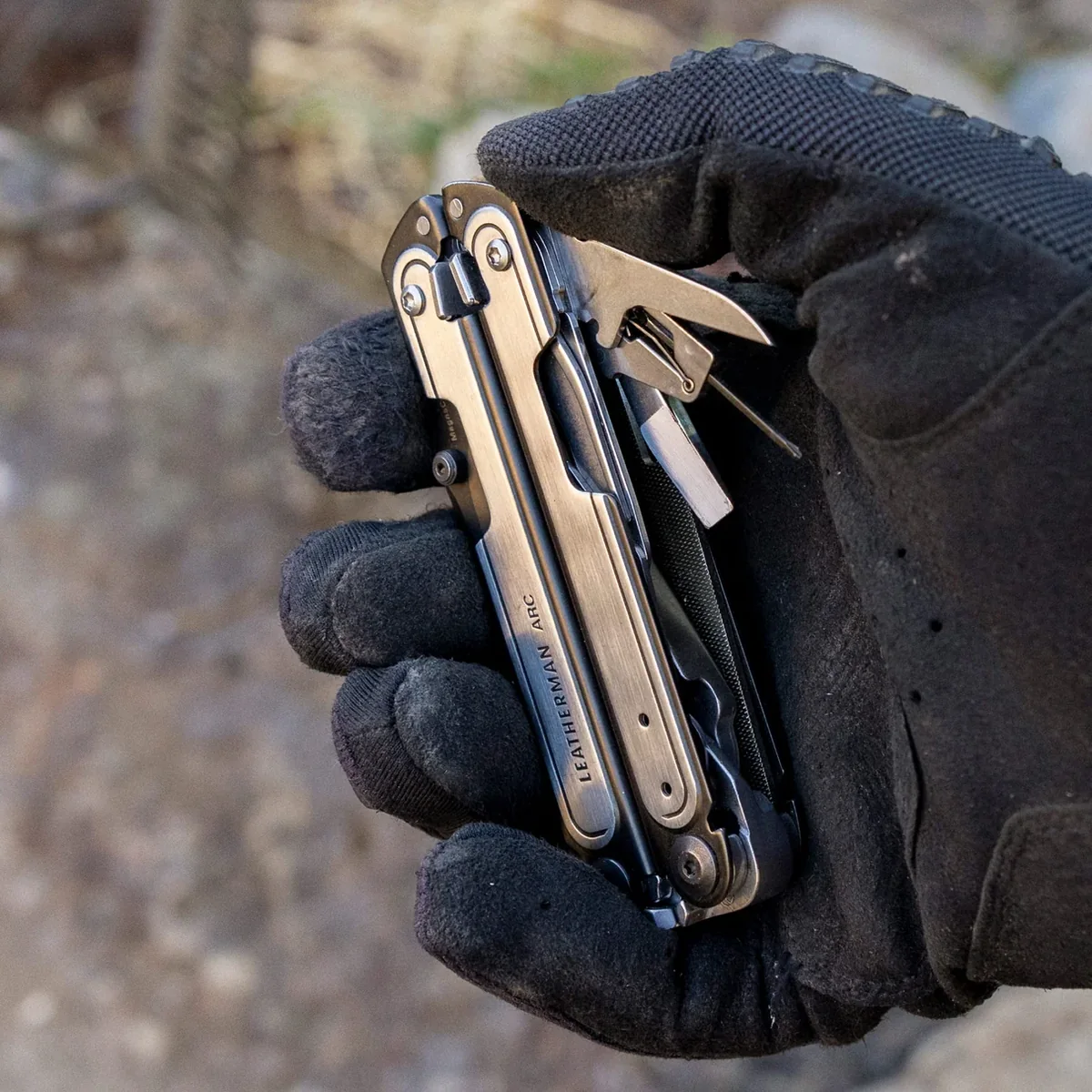 Leatherman ARC held in a glove with several outside-accessible tools deployed