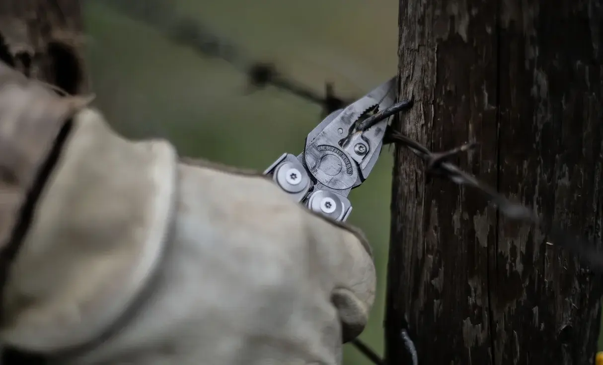 Leatherman Surge pliers gripping barbed wire on a wooden post
