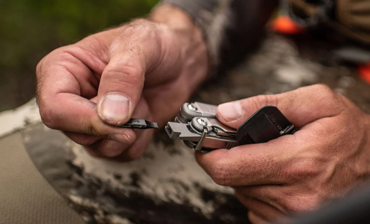 Hands fitting a removable flat bit to a Leatherman Wave+ driver