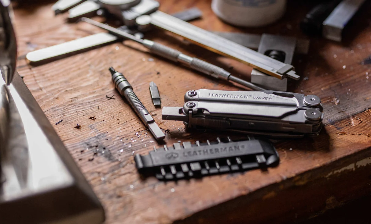 Closed Leatherman Wave+ beside a flat bit kit on a workbench