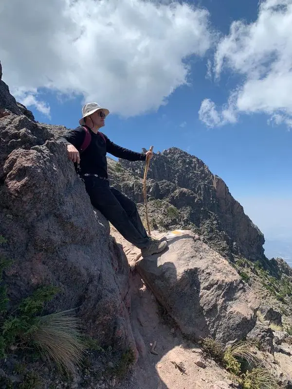 Hiker wearing Merrell Moab 3 Mid Waterproof boots on steep rocky terrain