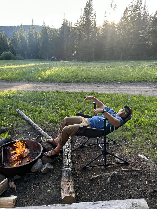 Camper reclining beside a campfire