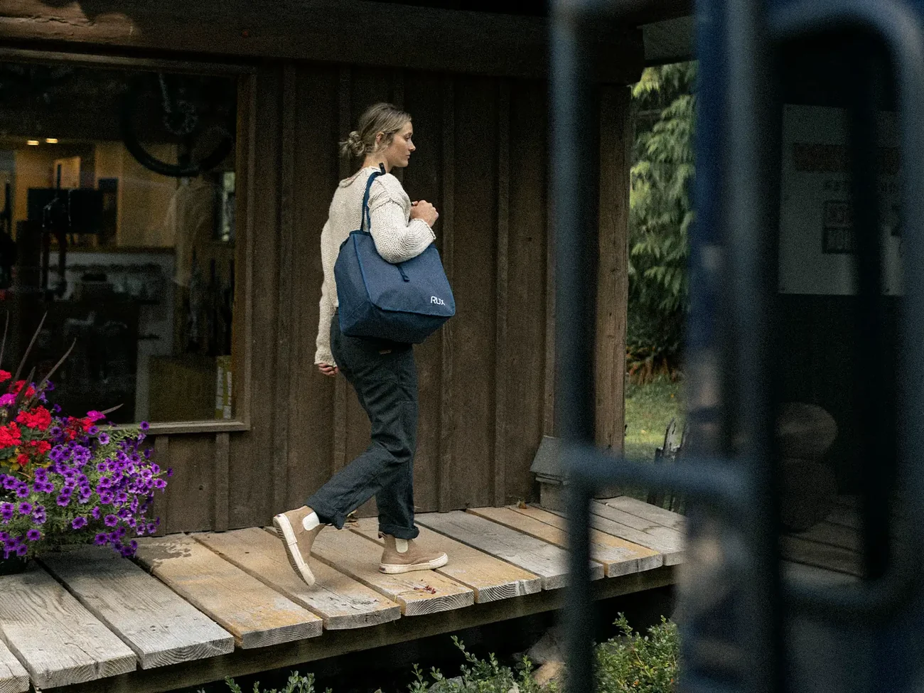 Navy RUX Bag 25L carried on a shoulder outside a cabin