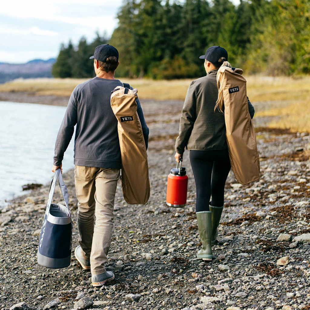 Two people carrying Trailhead Field Chairs in shoulder bags