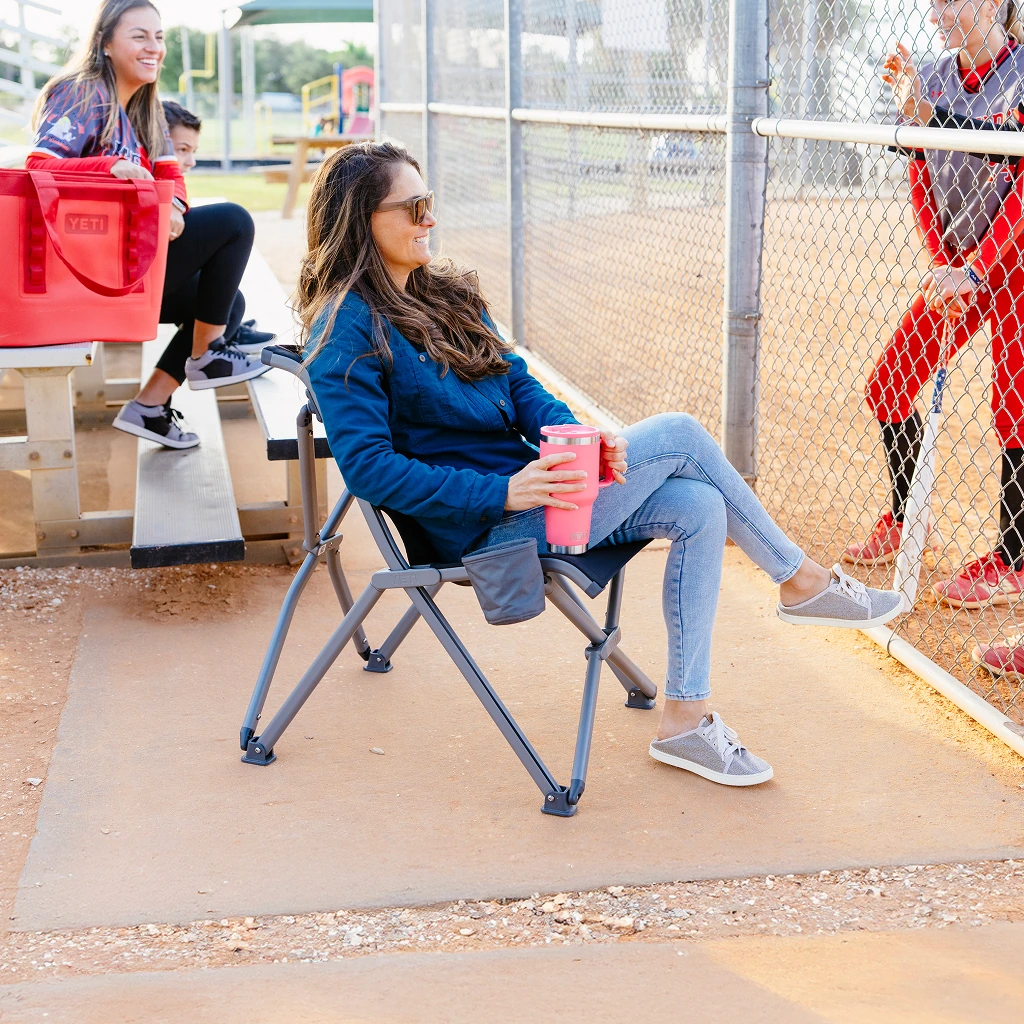 Person sitting in the Trailhead Field Chair at a sports field
