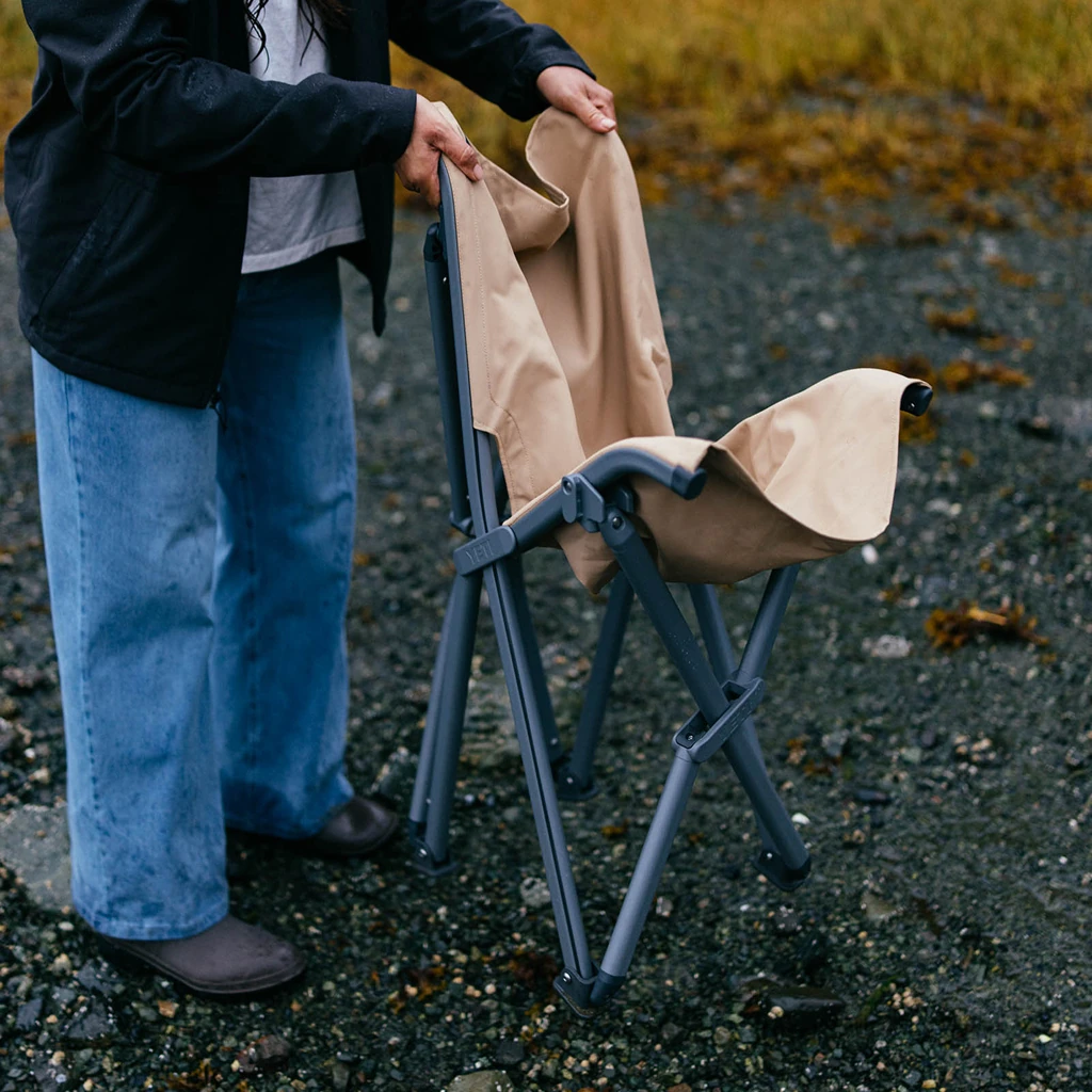 Person folding the Trailhead Field Chair on gravel